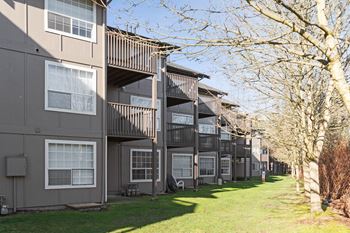 A row of apartment buildings with balconies and grass and trees